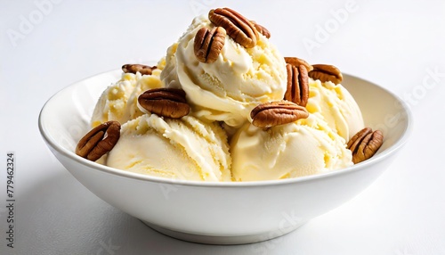 butter pecan nut ice cream, round scoops in small plain white bowl with pecans scattered on top of the ice cream, isolated on white background.
