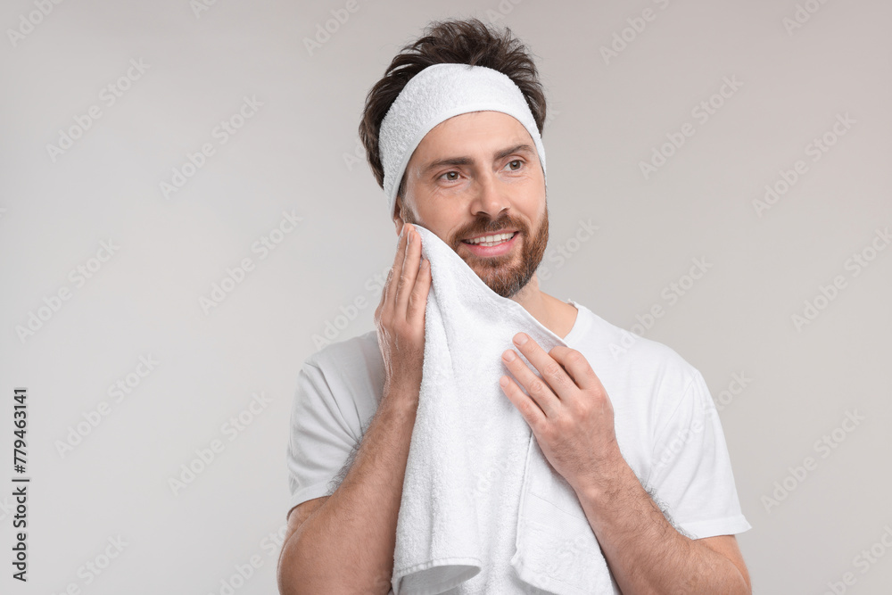 Washing face. Man with headband and towel on light grey background Washing face. Man with headband and towel on light grey background