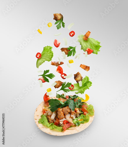 Delicious taco with flying ingredients on light background