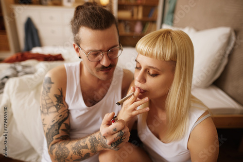 Caucasian couple smoking marijuana joint at home
