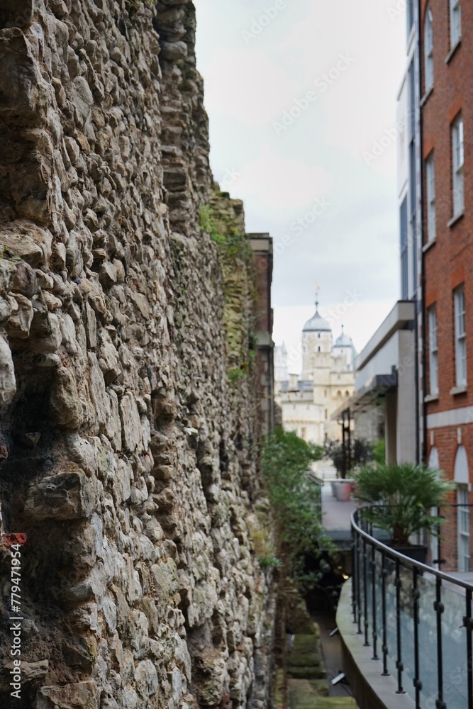 Historic cobblestone walls of the City of London, with the iconic Tower of London visible in the background  