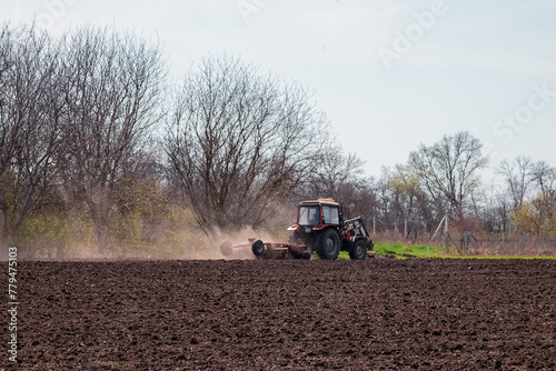 A farmer on a tractor prepares the land with a cultivator for sowing seeds. Agriculture  farming.