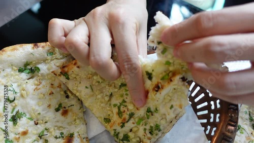 Hands eating garlic naan dip bread in to Indian curry South Asia food photo