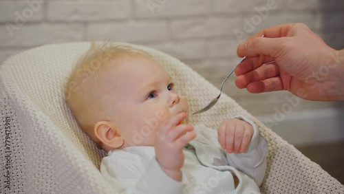Feeding the baby vegetables or fruits. Father feeds baby boy with a small spoon, close-up. Newborn nutrition, baby food, healthy food. Diet diversity for children.