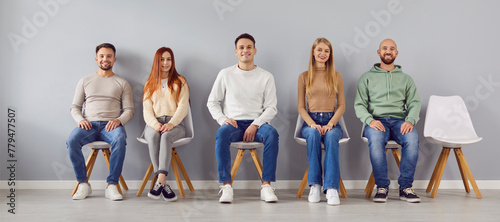 Group portrait of young smart people chair sitting in easy pose, one vacant place left. Diverse new company, together as team, friends gathered showing liking, affection, fellows in good relationships photo