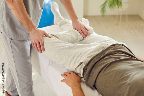 Close up of a caucasian man, therapist hands, massaging and stretching patient legs during a rehabilitation session in hospital office. Physical and physiotherapy aspects of the caregiver role.