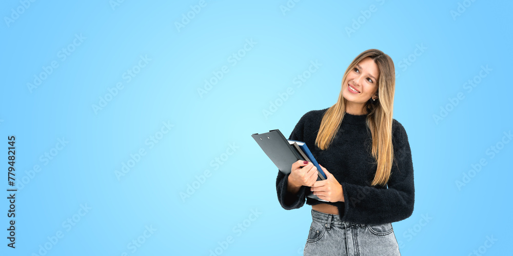 Happy woman student with clipboard and notebook in hands, copy space - obrazy, fototapety, plakaty 