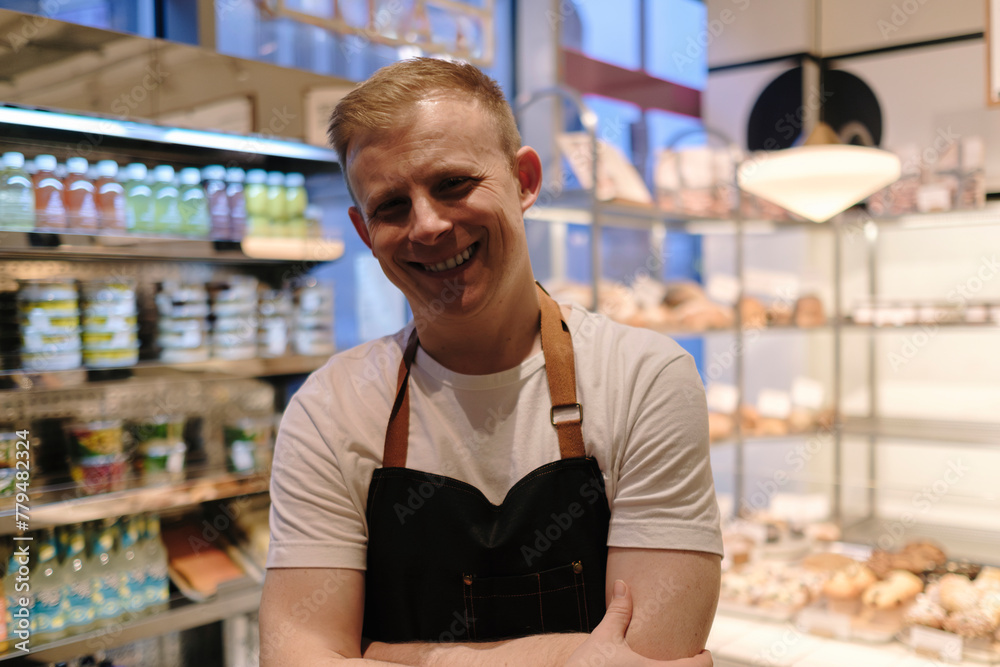 Happy baker standing with arms crossed in store