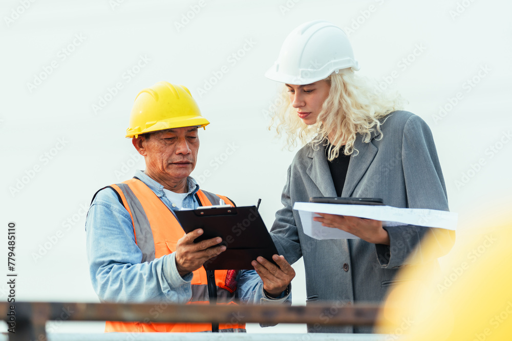 o people are looking at a tablet, one of them is wearing a yellow vest o people are looking at a tablet, one of them is wearing a yellow vest