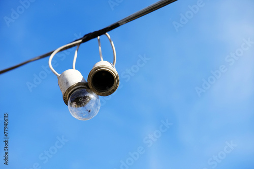 Equipped and electrical with light bulbs is hanging in the wind and sunlight on blue sky

