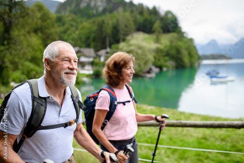 Portrait of active elderly couple hiking together in mountains. Senior tourists walking with trekking poles. © Halfpoint