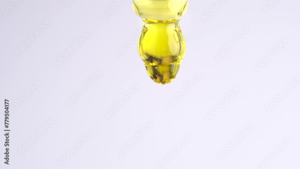 Essential oil drop dripping from pipette dropper, macro
