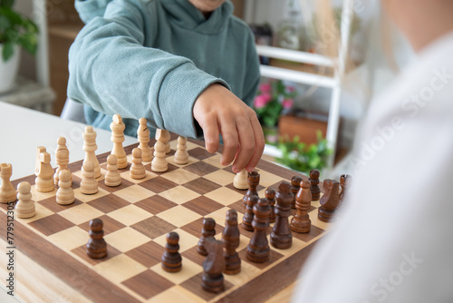 Children playing chess at home, one of them is making a move with a pawn. Education without screens