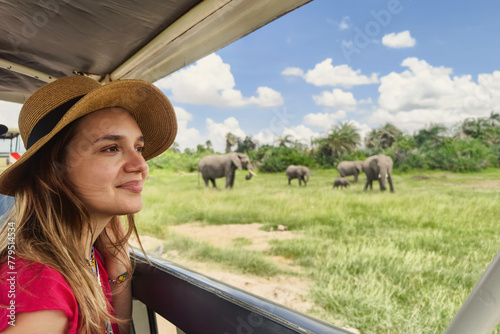 Photography A Caucasian girl in a hat looks at animals in the savannah