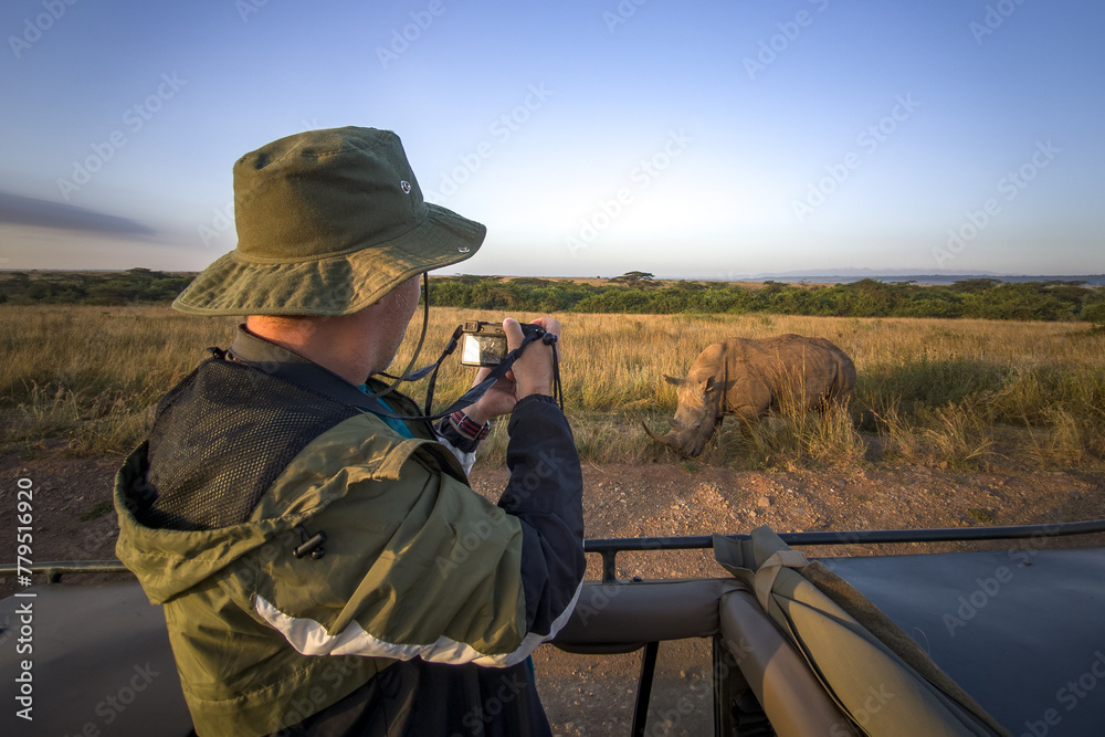 tourist photographs a wild leopard during a safari tour in Kenya and Tanzania. Concept Travel and adventure through wild Africa. man with a camera in an open-top safari car is traveling in Africa.