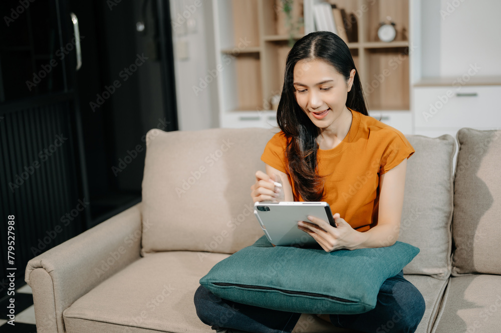 Asian woman using the smartphone and tablet on the sofa at home. Asian woman using the smartphone and tablet on the sofa at home.