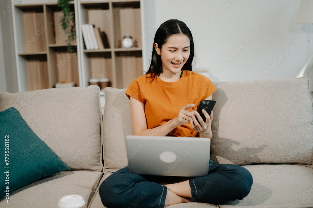  Female manager attending video conference and holding tablet, smatrphone and  cup of coffee on sofa at home