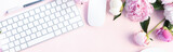 Flat lay home office workspace - modern keyboard with female accessories and fresh peony flowers, copy space on pink background
