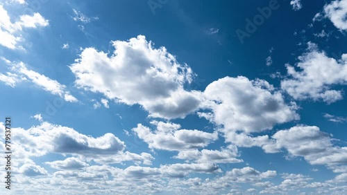 White fluffy clouds slowly float through the blue daytime sky timelapse. Beautiful skies are moving. Airy snow-white clouds move to the side.