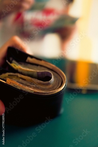 Vertical shot of a hand holding a thick wallet with cash