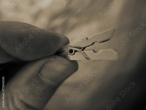 Macro grayscale of a wooden clothespin in the hand of a person on an isolated background photo