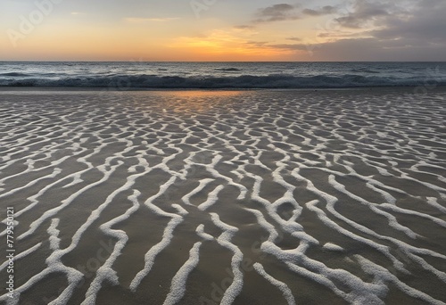 a beach with many white waves on the sand at sunset