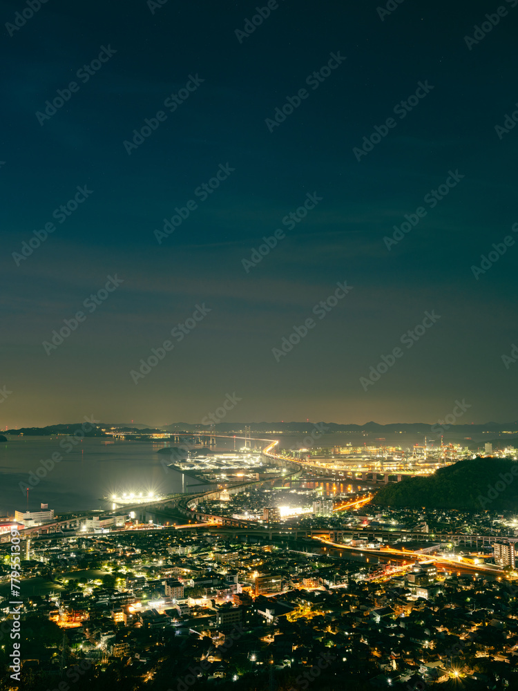Obraz premium Beautiful top view of urban city with many buildings by the sea at night, Great Seto Bridge in Sakaide City in Kagawa Prefecture in Japan, Travel or outdoor, High resolution over 50MP