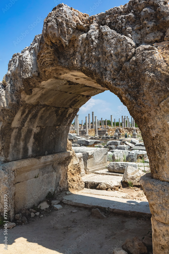 Stone archway framing Perge ruins under clear blue sky. Aksu, Antalya, Turkey (Turkiye)