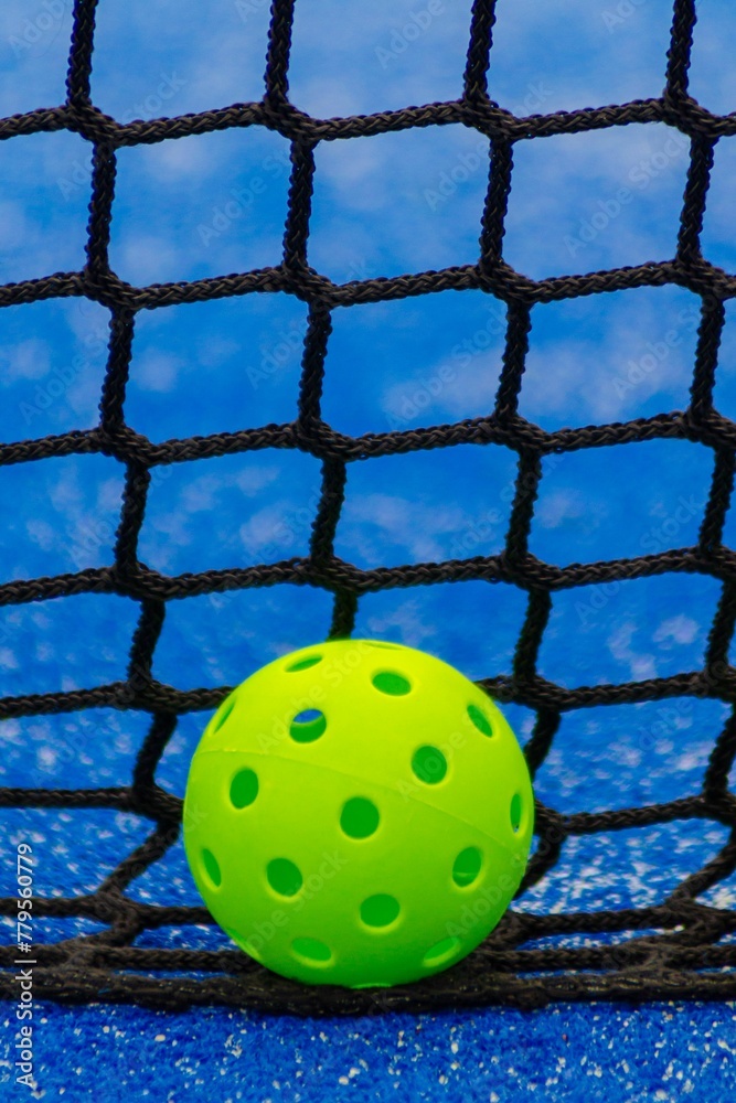 Pickleball ball in front of a blue court net, racket sports Pickleball ball in front of a blue court net, racket sports