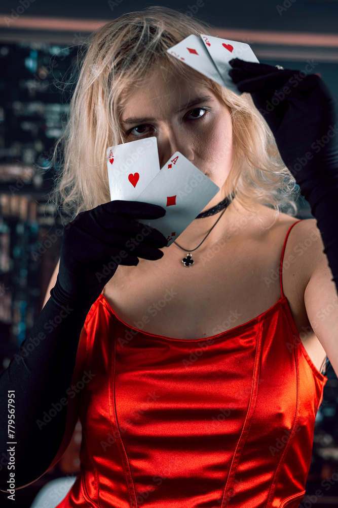 Φωτογραφία Pretty young woman in red dress and hat holding aces poker card at casino