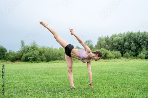Portrait of young fitness trainer practicing pilates exercise in quit summer park  morning time