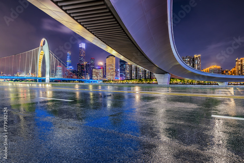 Asphalt road and bridge with modern city buildings scenery at night in Guangzhou. Road and city buildings background after rain.