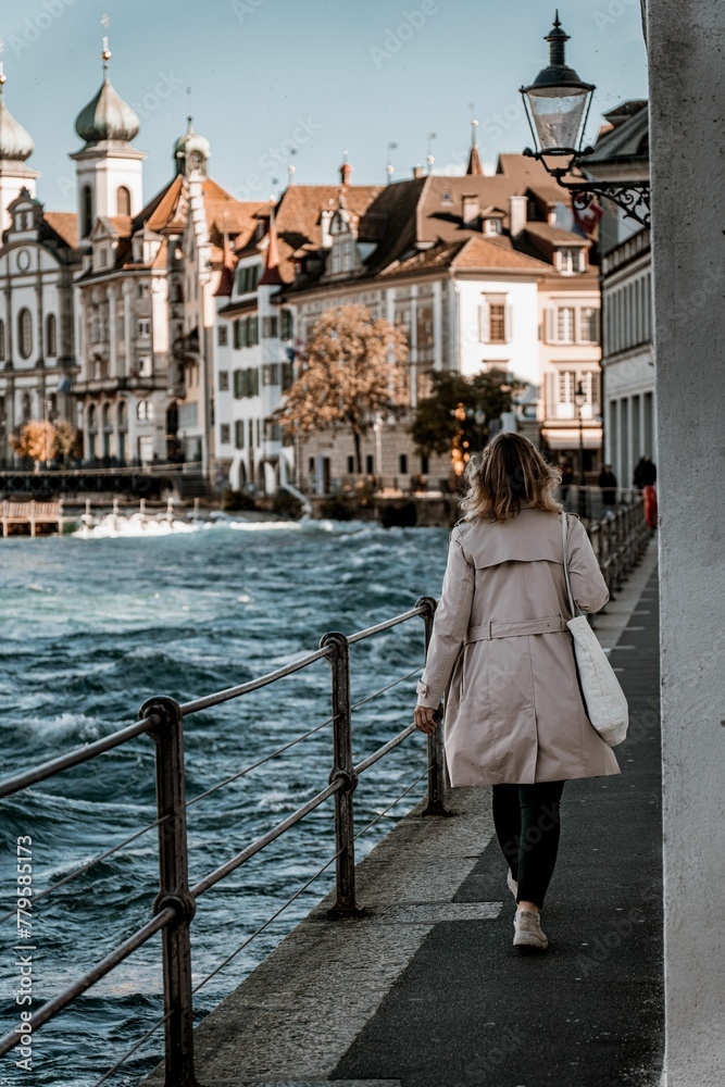Vertical shot of a woman walking in Lucerne with Jesuit Church in the background, Switzerland