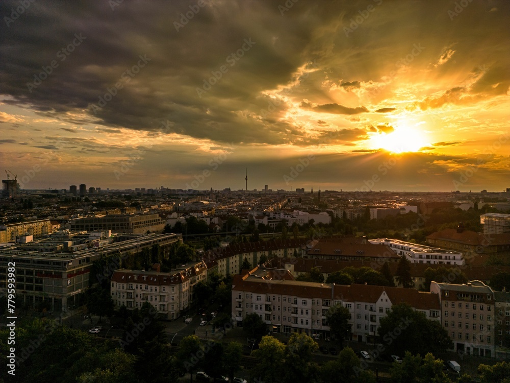 Bright sun shining behind sunset clouds over Berlin cityscape