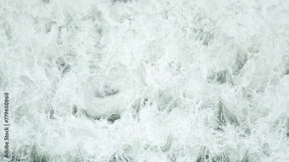 Top view of ocean waves hitting the stones o beach in slow motion Top view of ocean waves hitting the stones o beach in slow motion