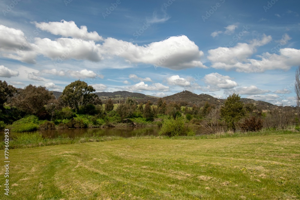 River flowing through green landscape under a blue cloudy sky on a sunny day River flowing through green landscape under a blue cloudy sky on a sunny day