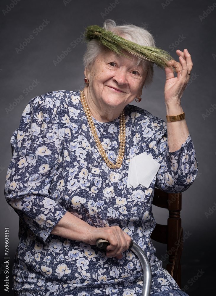 Smiling elderly woman with wreath on head posing in studio