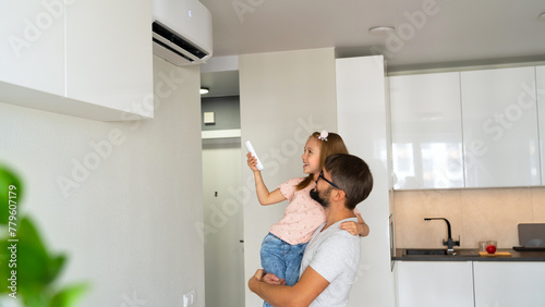 Happy family father and child adjust comfortable temperature of air conditioner using remote control in apartment
