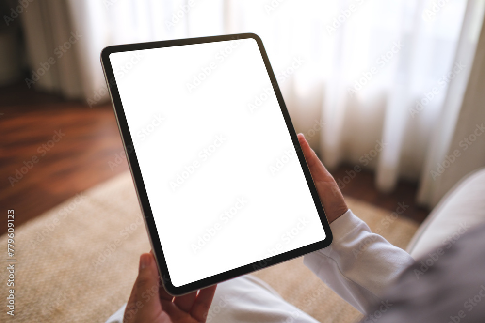 Mockup image of a woman holding digital tablet with blank desktop screen while sitting on a sofa at home - obrazy, fototapety, plakaty 