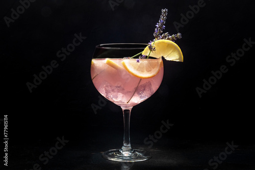 Fancy cocktail with fresh fruit. Gin and tonic drink with ice at a party, on a black background. Alcohol with lavender and lemon