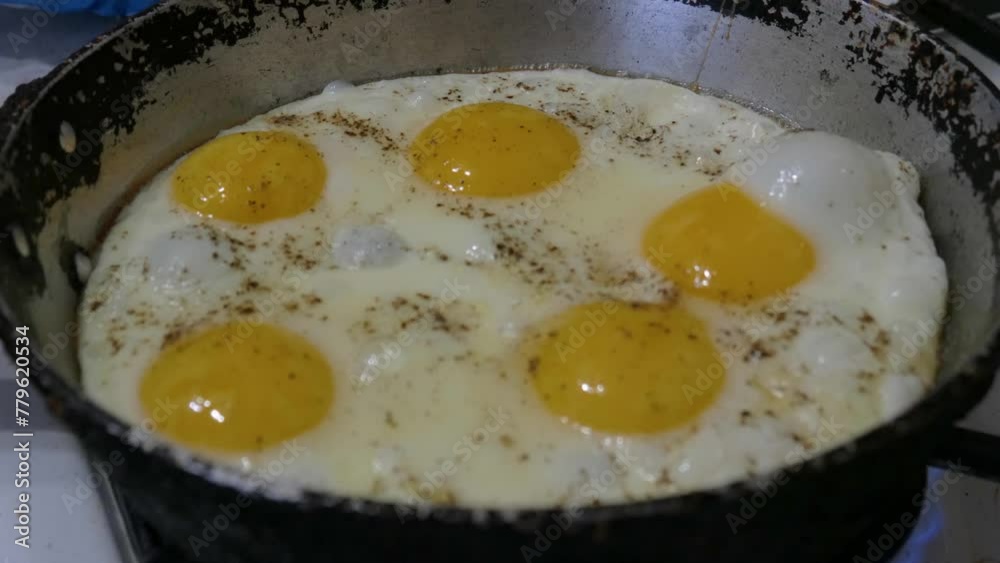 Cooking breakfast on a gas stove in the kitchen. Cracked chicken egg in a frying pan. Eggs frying in an old frying pan in close-up. Cooking breakfast on a gas stove in the kitchen. Cracked chicken egg in a frying pan. Eggs frying in an old frying pan in close-up.
