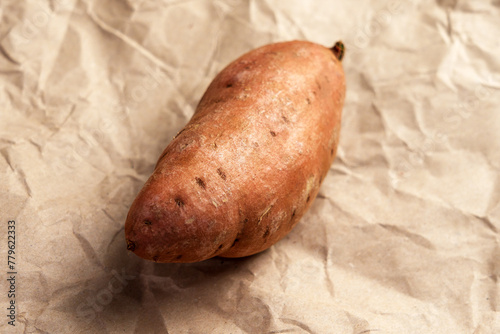 Unpeeled sweet potato on paper. Fresh batata root