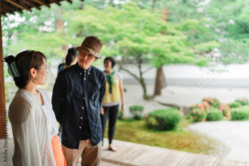 Japanese friends engage in conversation while walking through the tranquil setting of a traditional Japanese garden photo