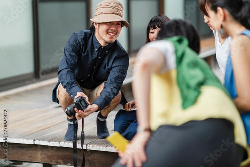 A Japanese photographer interacts with his subjects during an outdoor photo session, exchanging smiles and capturing the cheerful essence of the moment photo
