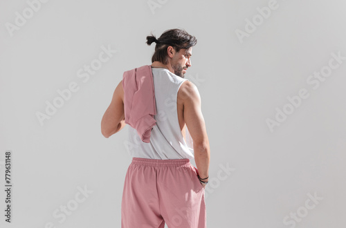 behind view of muscular fit guy with hair tail holding hand in pocket