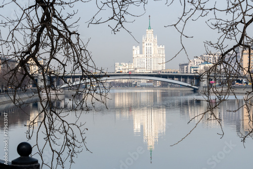 City embankment. Beautiful houses are reflected in the calm river. The concept of early spring in a big city.