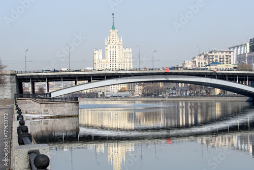 City embankment. Beautiful houses are reflected in the calm river. The concept of early spring in a big city.