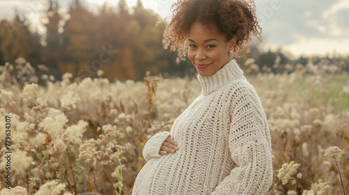 Pregnant woman in knitted sweater holding belly photo