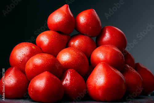 Heap of red, fresh, aromatic, ripe tomatoes with water drops on a dark background