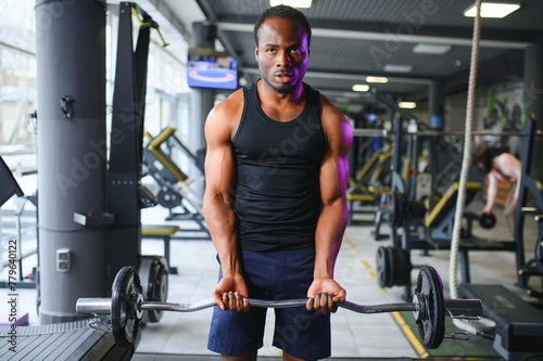 Athletic black guy making weightlifting or powerlifting at modern gym